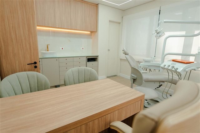 Área de conversa do consultório com mesa, cadeiras e equipamentos odontológicos