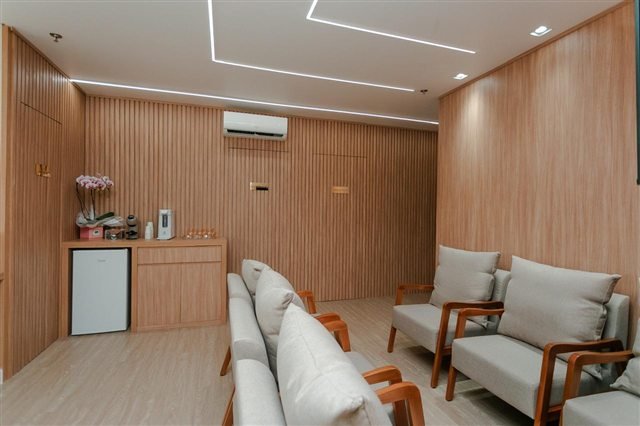 Recepção da Touma Odontologia e Estética com poltronas e acabamento em madeira
