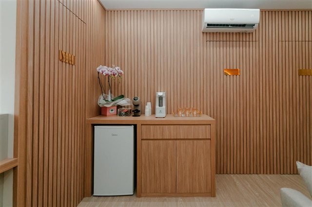 Detalhe da recepção com painel ripado, café e ambiente climatizado